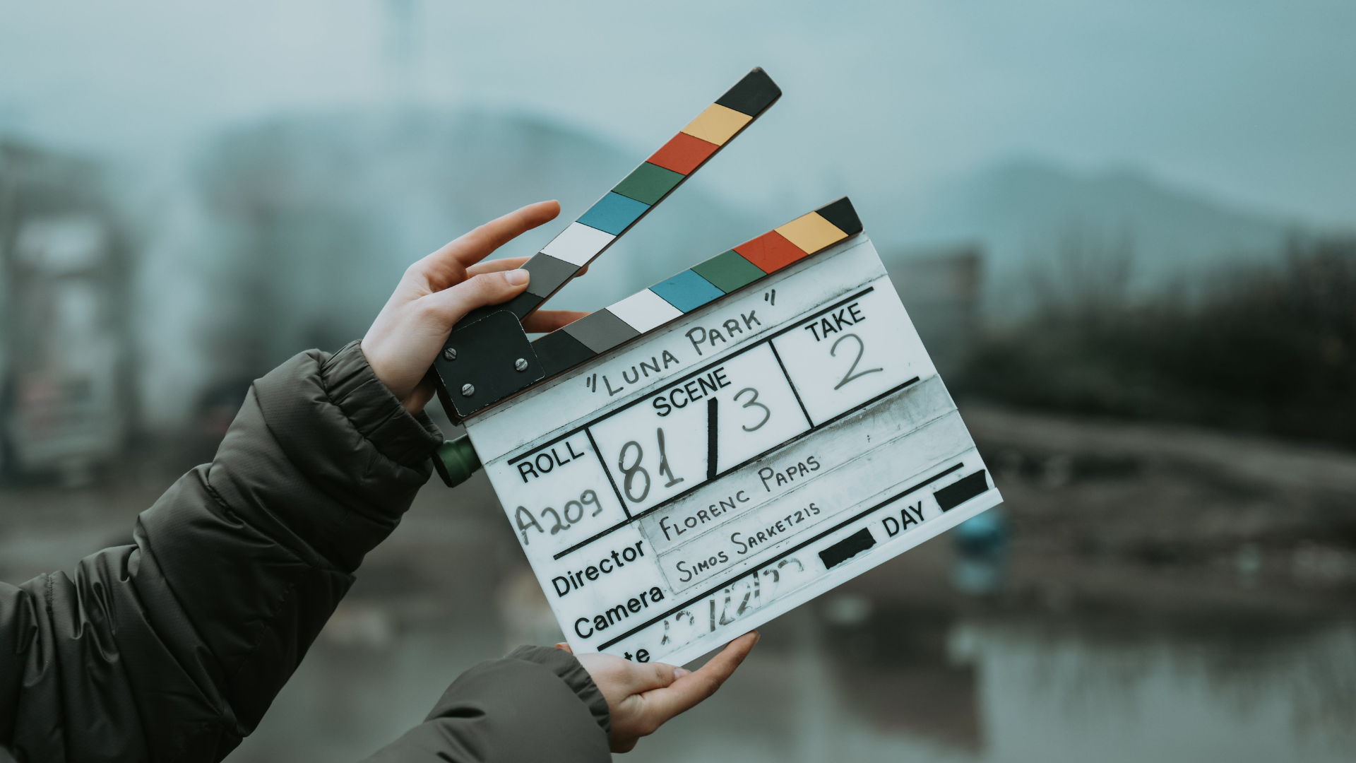 A crew member holds up a film clapperboard marked Luna Park, scene 81, take 2, on location